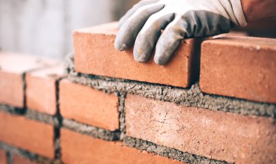 Close up of industrial bricklayer installing bricks on construction site